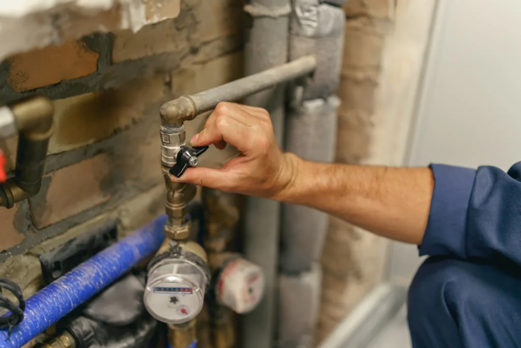 Fontanero ajustando una llave de paso junto a los contadores de agua
